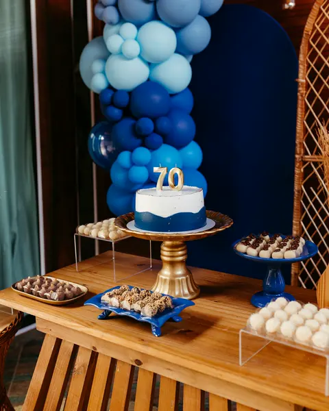 Mesa de aniversário com bolo, doces e balões azuis